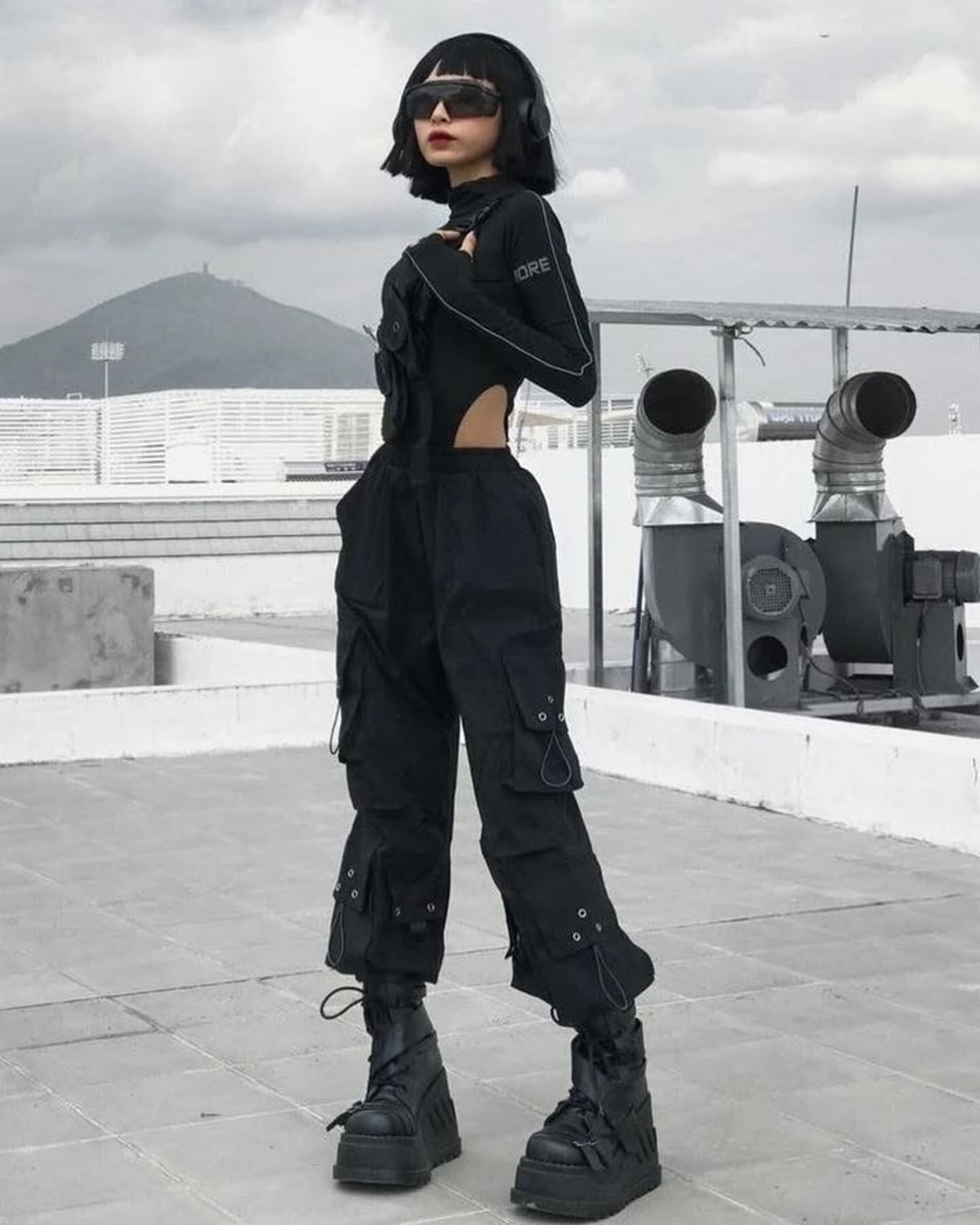 Berlin Techno outfit — black visor sunglasses, long-sleeve cutout bodysuit, black cargo utility pants, black platform combat boots