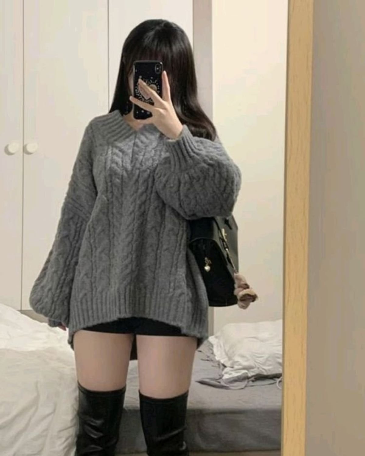 E-Girl outfit — oversized gray cable-knit sweater, black bike shorts, black over-the-knee platform boots, black structured shoulder bag, phone case with celestial print