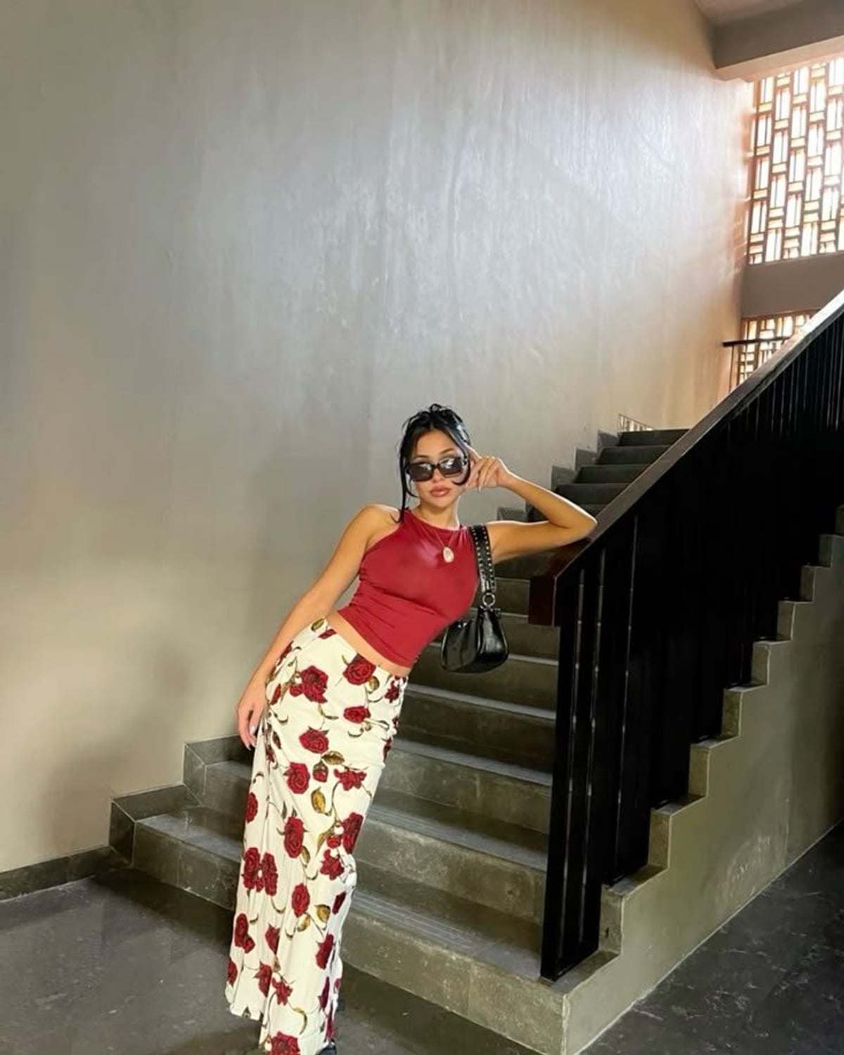 Mexico City Fresa Modern outfit — slim rectangular black sunglasses, gold pendant necklace, red halter crop top, rose-print low-rise maxi skirt, black pointed-toe ankle boots