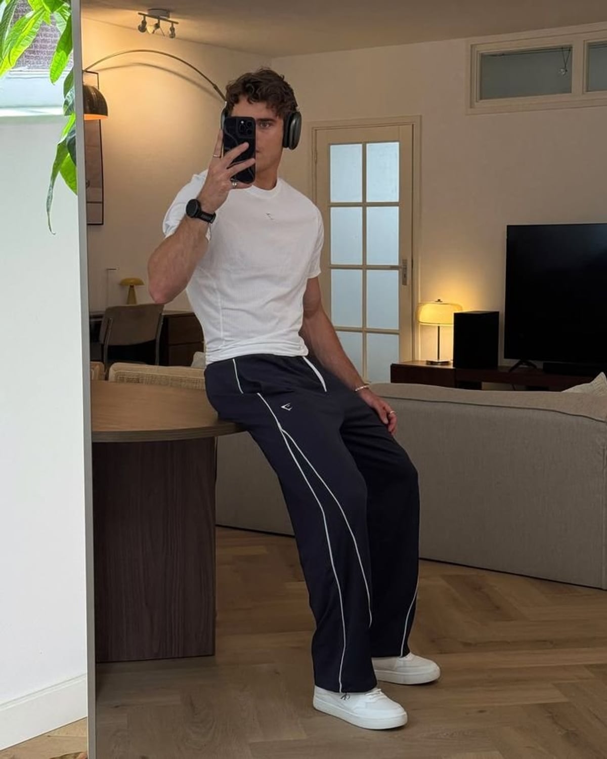 Retro Gymcore outfit — men's white crewneck t-shirt, men's black smartwatch, men's navy wide-leg track pants with white piping, men's white leather low-top sneakers